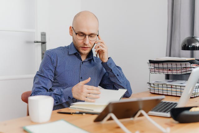 person talking on the phone while looking at a notebook